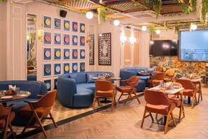 En restaurang med blå sittplatser, ett golv i fiskbensmönster och en vägg dekorerad med runda tallrikar.