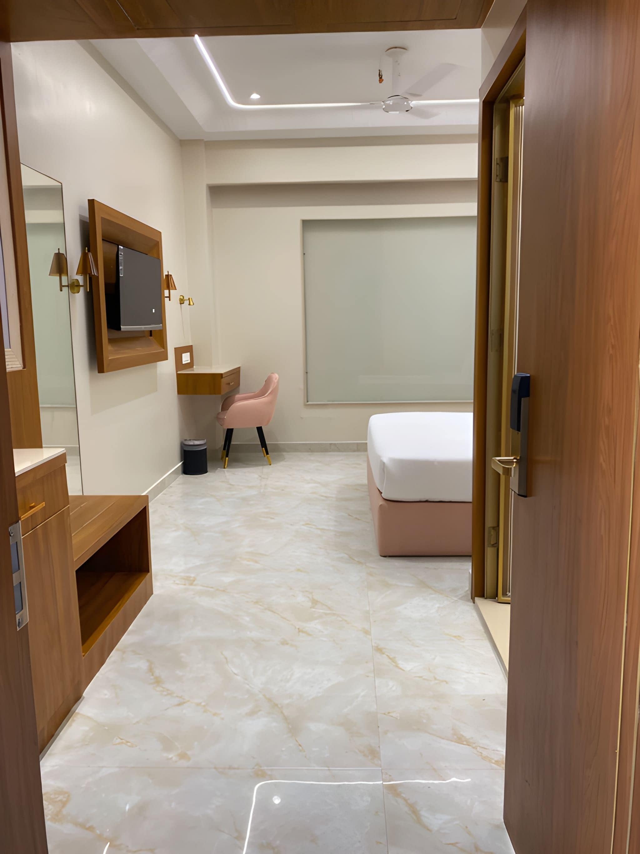 Un dormitorio moderno con una cama, un tocador con espejo, una silla rosa y un ventanal grande.