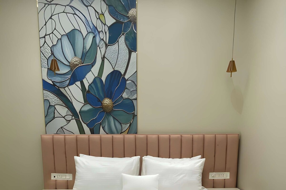 A bedroom with a large bed, a headboard, two bedside tables, and a wall-mounted light fixture.