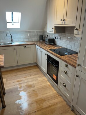 A kitchen with a sink, toaster, oven, and cabinets.