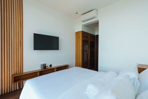 Ein Hotelzimmer mit Bett, Wand-Fernseher, Holzschrank und eingebautem Regal.