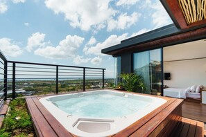 Ein moderner Außenbereich mit Whirlpool, einer Holzterrasse und einer Aussicht auf die Landschaft.