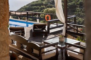 A wooden deck with a pool, lounge chairs, and a glass table. - Villa Lithos by Your Villa (Aptera)
