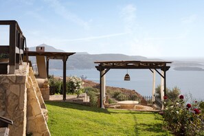 A stone wall, a pergola with a bell, and a view of the sea. - Villa Lithos by Your Villa (Aptera)