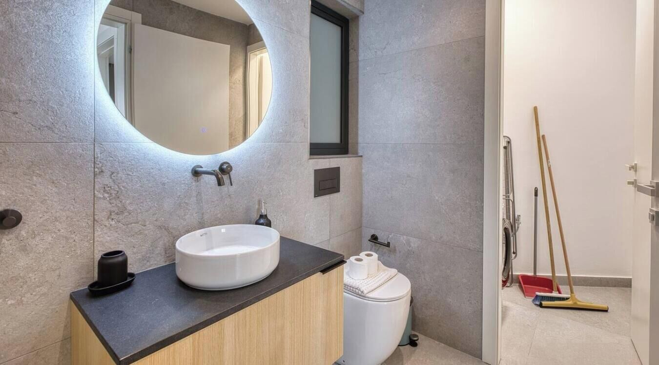 Un bagno moderno con uno specchio rotondo, un lavabo e un water.