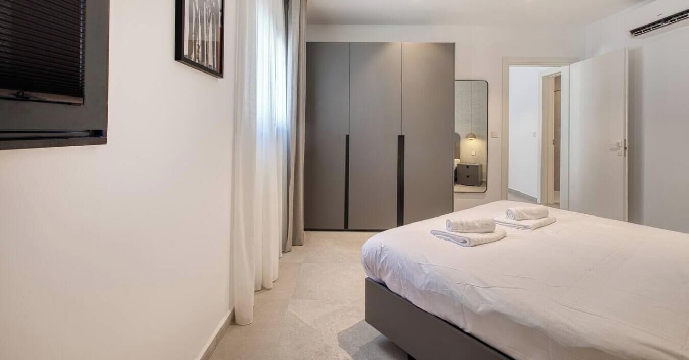 Una camera da letto moderna con un letto, un armadio e uno specchio.