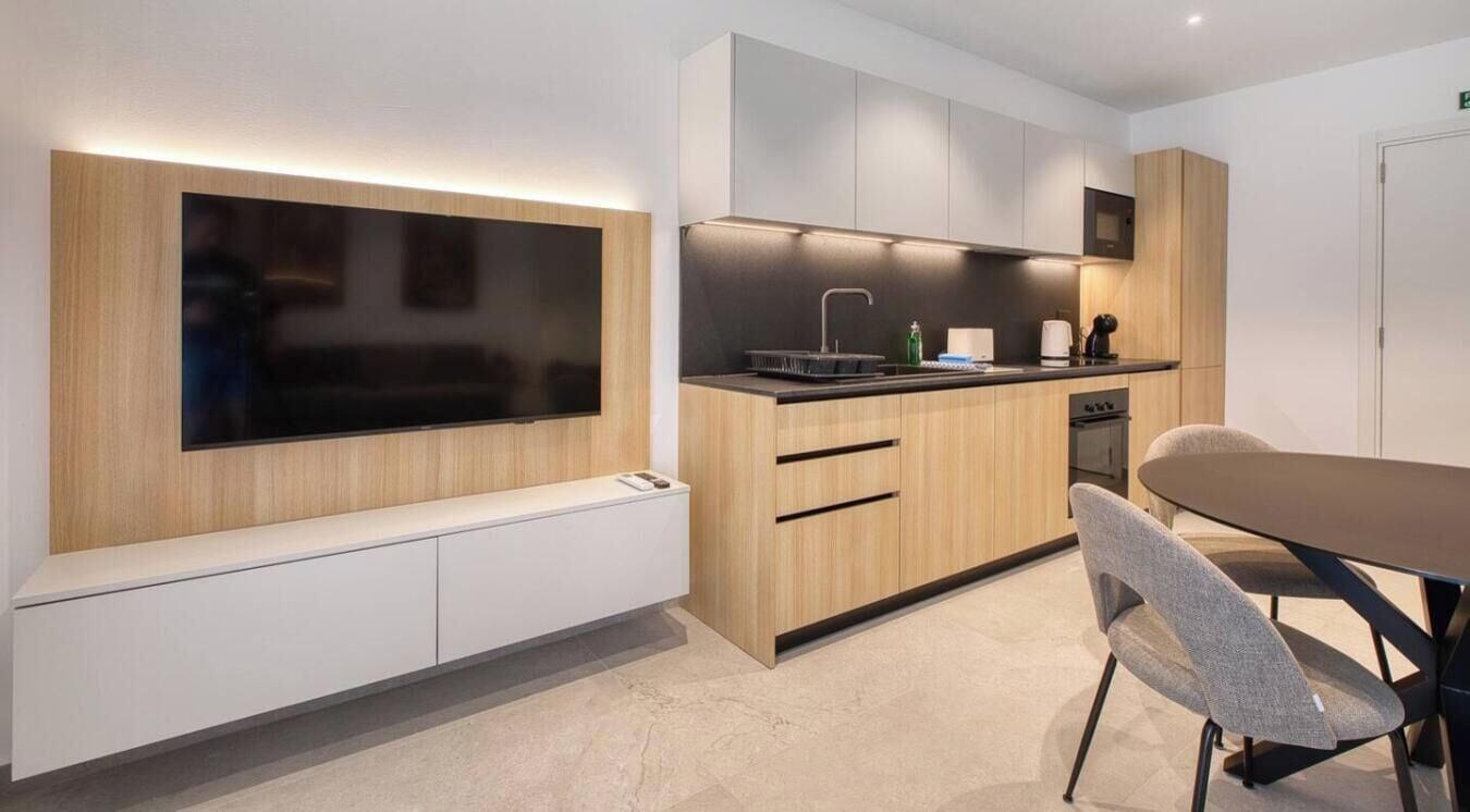 A modern kitchen with a built-in TV, wooden cabinets, and a dining area with a table and chairs.