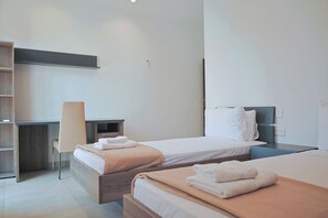 Ein Hotelzimmer mit zwei Betten, einem Schreibtisch und einem Stuhl.