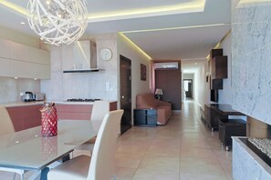 A modern kitchen with a dining area, a living space with a sofa, and a hallway leading to other rooms. - Gozo Countryside Views | 3 BR Apt. Sannat w/AC (Sannat)