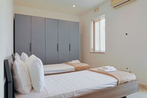 Ein Hotelzimmer mit zwei Betten, einem großen Kleiderschrank und einem Fenster mit Jalousien.