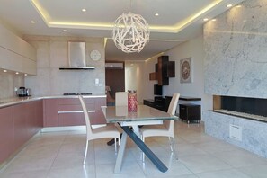 A modern kitchen with a dining area, a large chandelier, and a fireplace. - Gozo Countryside Views | 3 BR Apt. Sannat w/AC (Sannat)