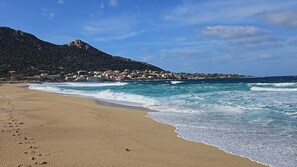 A beach with waves, a mountain, and buildings in the background. - Looking for peace and tranquility in the heart of Balagne, Corsica? (Monticello)