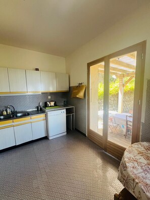 A compact kitchen with a sink, microwave, and a small refrigerator. There is a sliding glass door leading to an outdoor patio area. - Looking for peace and tranquility in the heart of Balagne, Corsica? (Monticello)