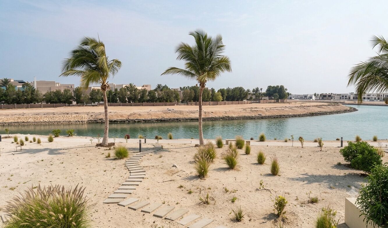 Ein sandiger Strand mit Palmen und einem Wasserabschnitt.