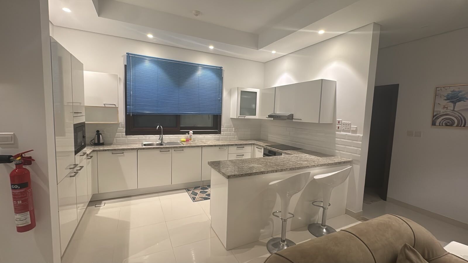 A modern kitchen with a central island, white cabinetry, and a built-in microwave.