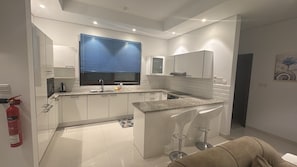 A modern kitchen with a central island, white cabinetry, and a built-in microwave.