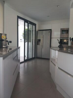 A modern kitchen with a built-in oven, refrigerator, and coffee maker. - Luxury 5-Bedroom Villa with a Huge 12.5-Meter Pool – 300 Meters from a Scenic Cove (Cala Baladrar) (Benissa)
