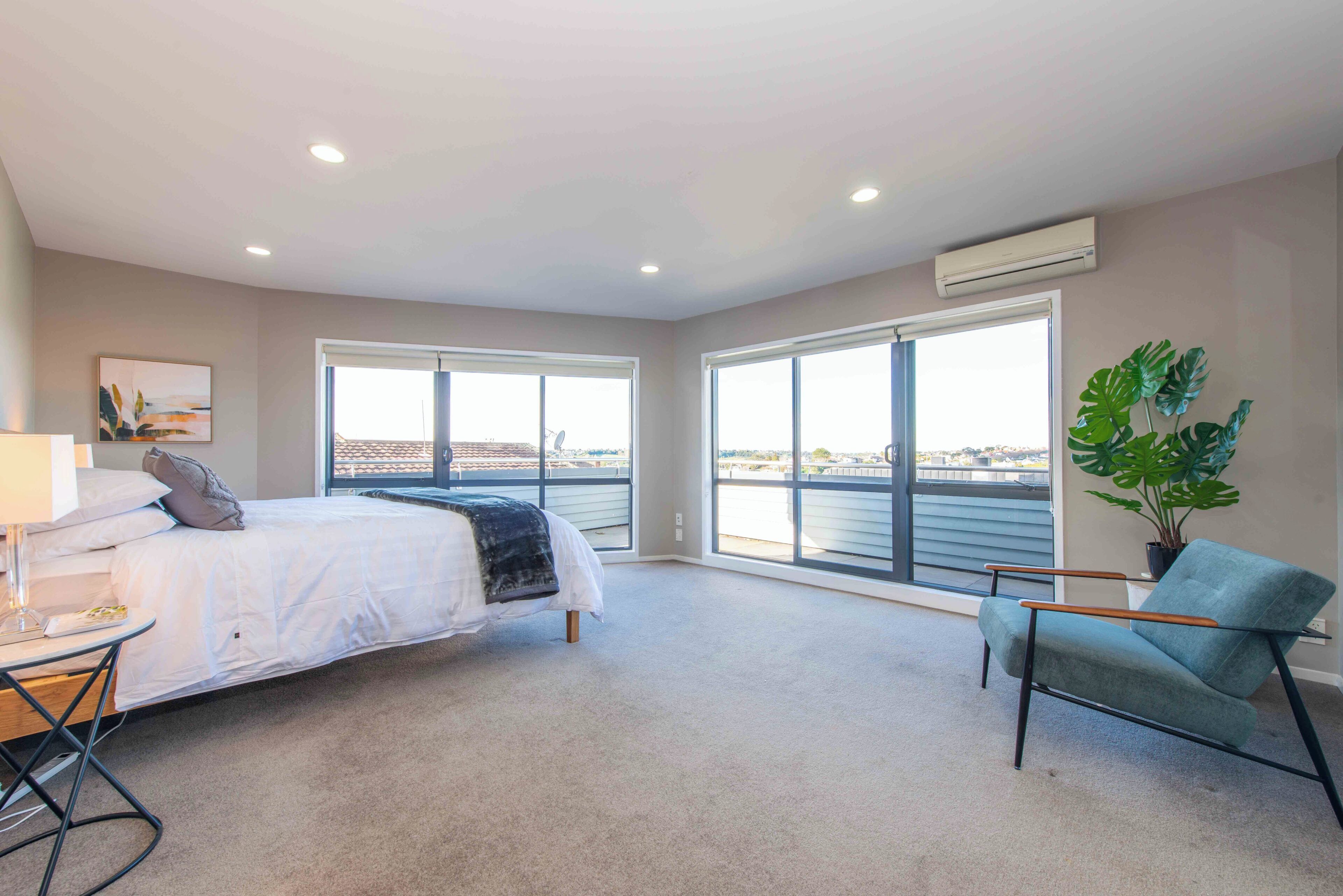 A bedroom with a bed, a chair, a desk, and a large window.