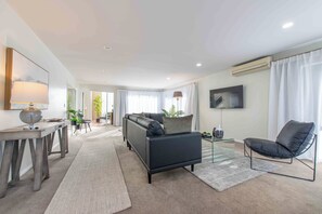 Un salon moderne avec un canapé, des fauteuils, une table basse et un téléviseur.
