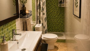 A bathroom with a white sink, a toilet, a shower, and a mirror.