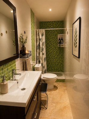 Un bagno con lavandino bianco, WC, doccia e specchio.