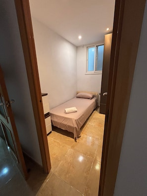 Una stanza piccola e stretta con un letto, una finestra e una porta.