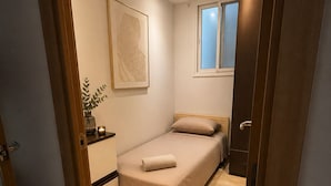 A bedroom with a bed, a bedside table, a window, and a door.