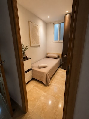 Una camera da letto con un letto, un comodino, una finestra e una porta.