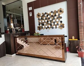 Un mostrador de recepción con un diseño geométrico en la pared de fondo.