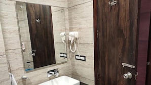 A bathroom with a white sink, dark countertop, and a wooden door. - Ramoji Resorts (Hathras)