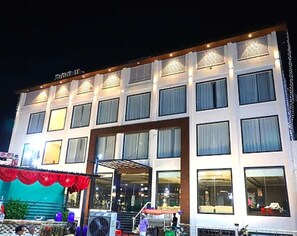 Un hotel de varios pisos con una entrada central, ventanas amplias y una zona exterior cubierta.
