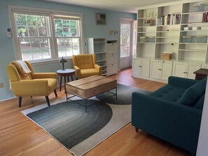 Un salon comprenant un canapé, des fauteuils, une table basse et une bibliothèque.