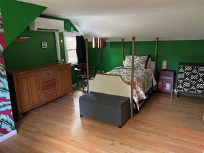 Une chambre à coucher avec un lit, une commode en bois, une chaise et une petite table.