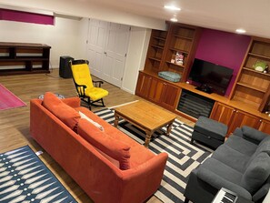 Ein Wohnzimmer mit einer Couch, Sesseln, einem Couchtisch, einem Fernseher und einem Kamin.