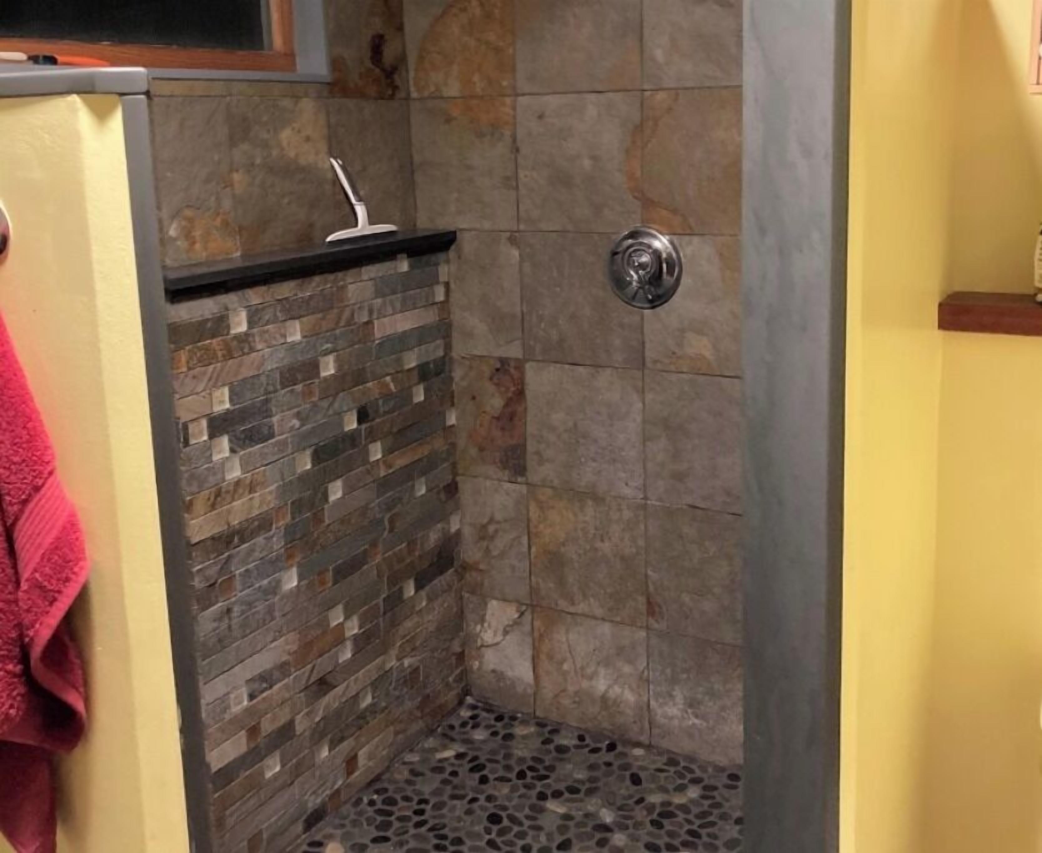 walk-in river-stone shower with rainfall + handheld shower heads. 