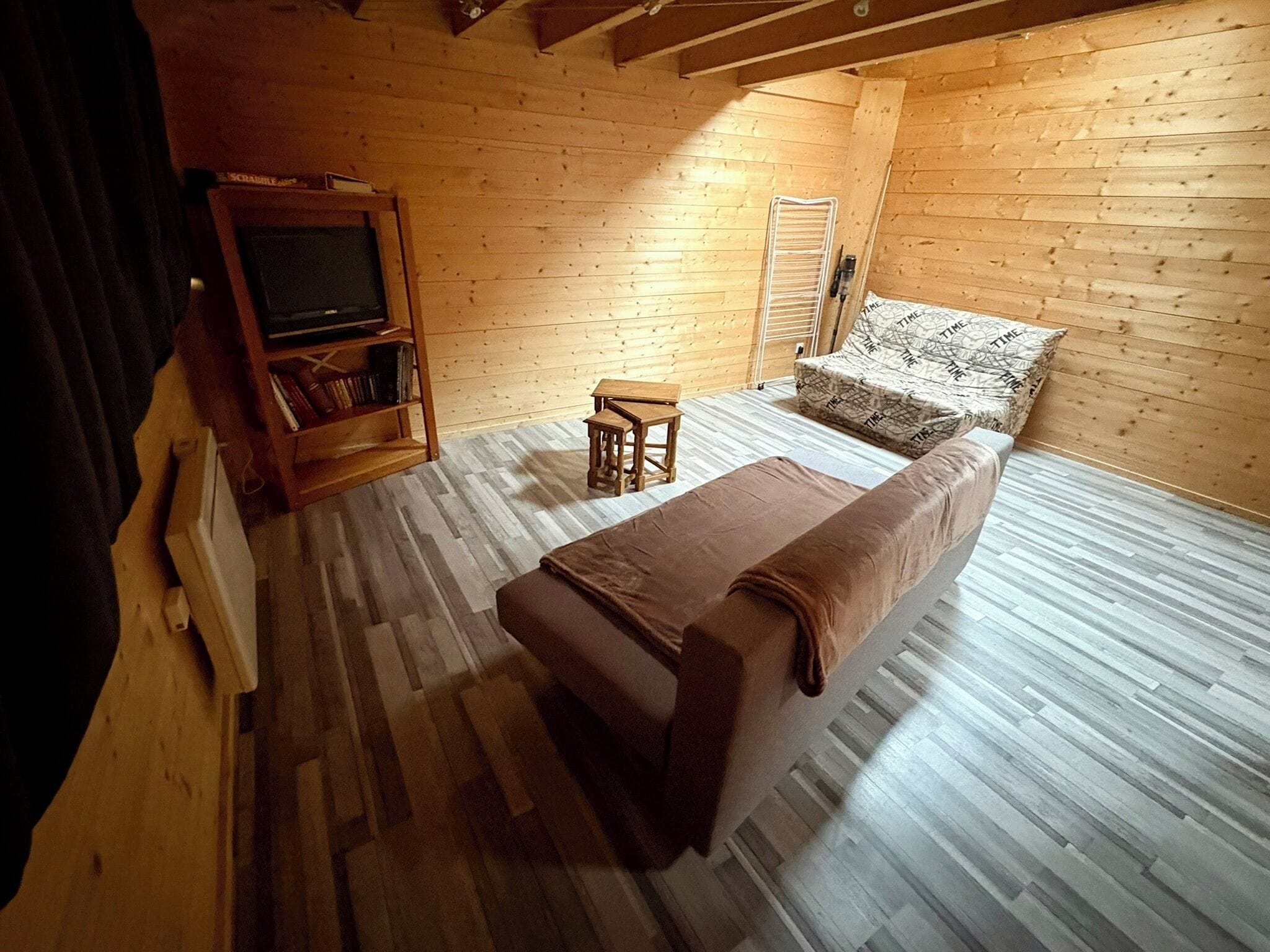 Um quarto aconchegante com uma cama, uma mesinha, uma estante de livros e uma televisão.