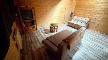Um quarto aconchegante com uma cama, uma mesinha, uma estante de livros e uma televisão.