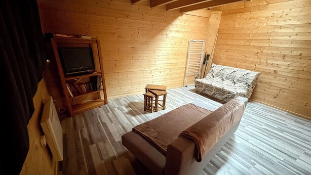 A cozy room with a bed, a small table, a bookshelf, and a television.