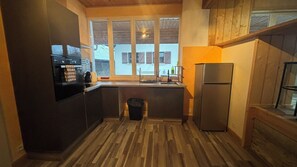 A compact kitchen with a built-in oven, a sink, and a refrigerator. - Vrbo Property (Sainte-Hélène-sur-Isère)