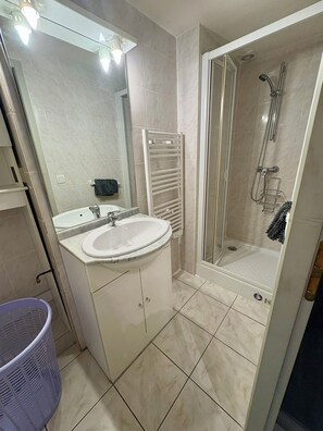 A bathroom with a sink, mirror, shower, and a towel rack. - Vrbo Property (Sainte-Hélène-sur-Isère)