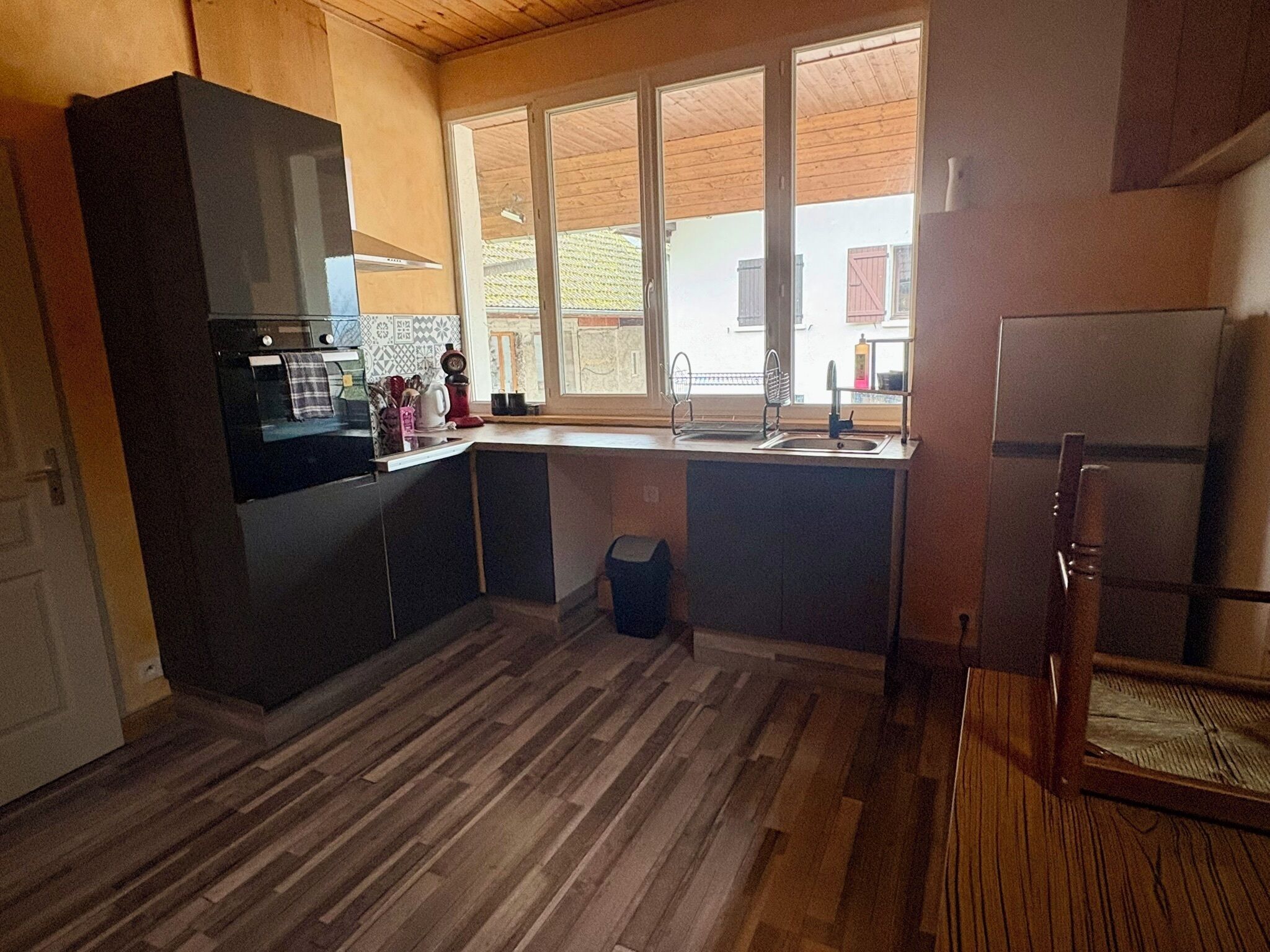 Una cucina moderna con pavimento in legno, forno integrato e finestra vista su zona residenziale.
