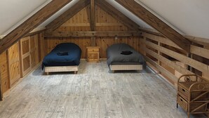 A small attic bedroom with two beds, wooden walls, and a sloped ceiling.