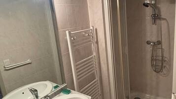Ein Badezimmer mit Waschbecken, Spiegel, Handtuchhalter und Duschkabine.