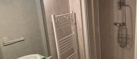 Un baño con lavamanos, espejo, toallero y cabina de ducha.