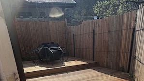 A wooden deck with a metal table and chairs, surrounded by a wooden fence.