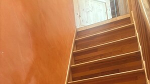 A wooden staircase with a handrail, leading to a landing with a white door.