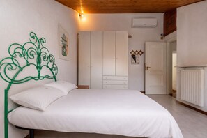A bedroom with a bed, a wardrobe, a radiator, and a door. - Grande Giove – Spacious Family & Bike Home in the Heart of Finalborgo (Finale Ligure)