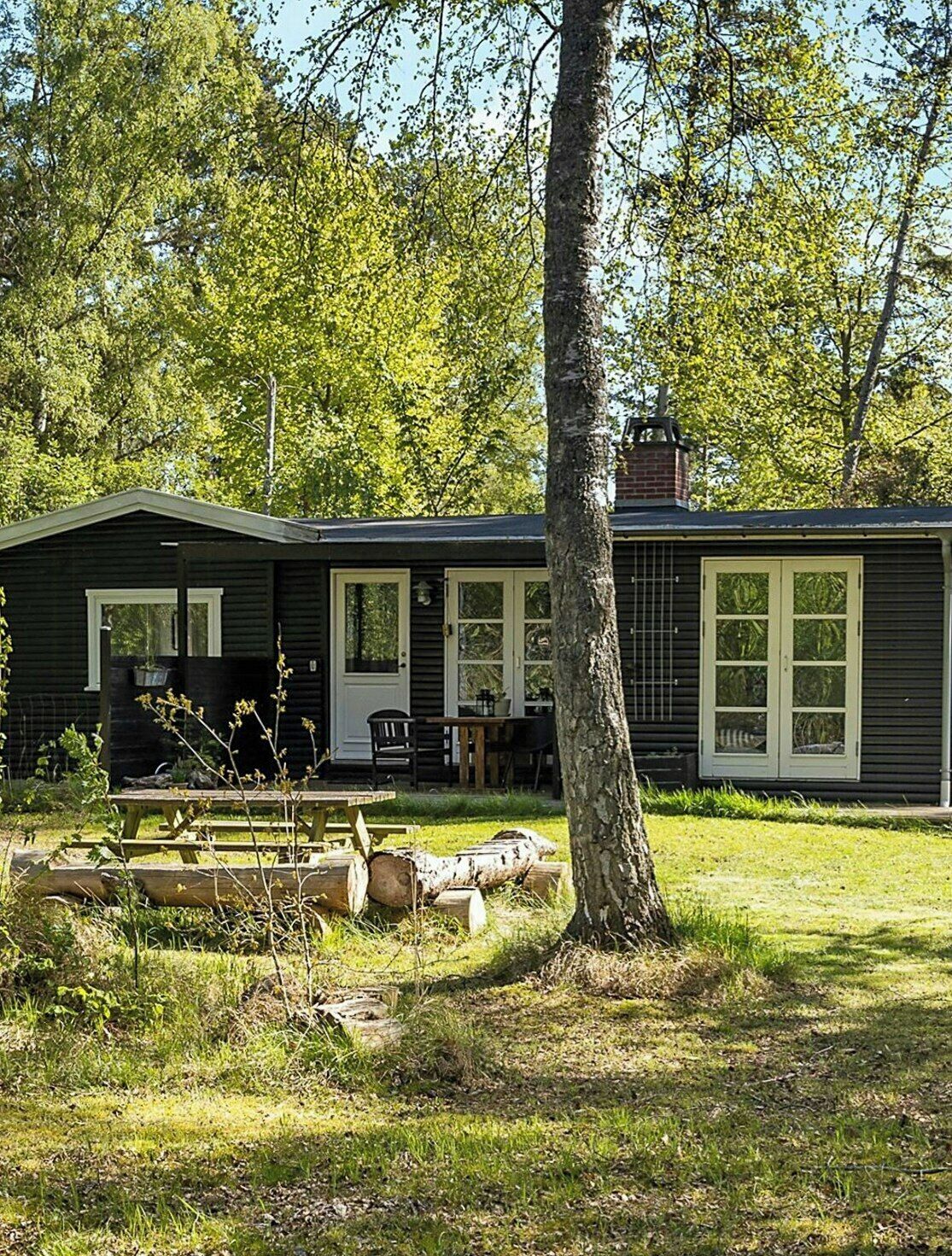 Une cabane de plain-pied avec un porche à l’avant, une cheminée et une petite terrasse.