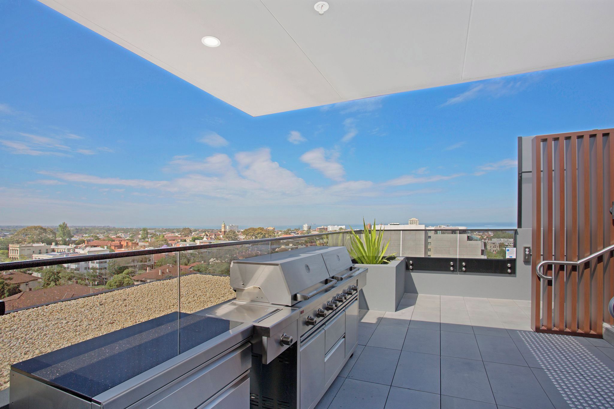 Un patio en la azotea con una parrilla, vistas panorámicas de la ciudad y un portón de madera.
