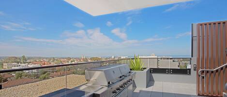 Un patio en la azotea con una parrilla, vistas panorámicas de la ciudad y un portón de madera.